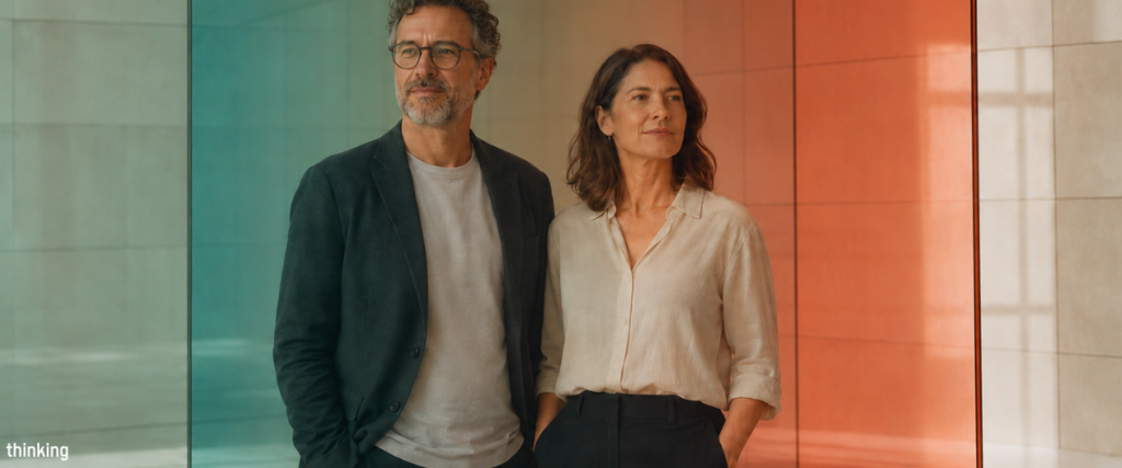 Male and female leaders standing together between overlapping colored glass panels, representing the ability to hold opposing leadership qualities